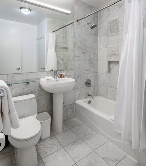 A modern bathroom with a toilet, sink, bathtub, and shower.