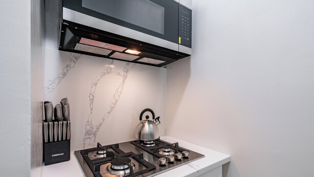 A modern kitchen with a gas stove, a kettle, and a knife block. - Near Central Park | Pet-Friendly & Hardwood Floors (New York)