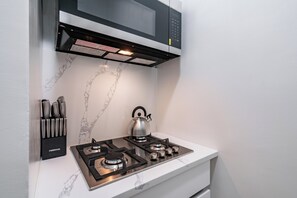 A modern kitchen with a gas stove, a kettle, and a knife block.