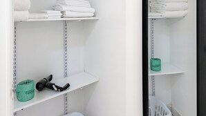 A clean, white bathroom with shelves holding towels and a basket. - Near Central Park | Pet-Friendly & Hardwood Floors (New York)