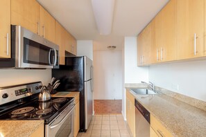 A kitchen with wooden cabinets, stainless steel appliances, a microwave, stove, refrigerator, and a dishwasher.