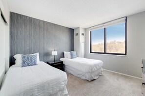 A modern bedroom with two beds, a large window, and a grey accent wall. - 2 Bedroom Steps from Metro-North to NYC (White Plains)