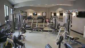 Un gimnasio con cintas de correr, elípticas y equipo de pesas.