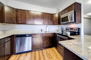 Une cuisine avec des meubles en bois foncé, des appareils électroménagers en acier inoxydable et un plan de travail en granit.