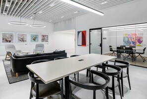 A modern office space with a white ceiling, black furniture, and artwork on the walls.