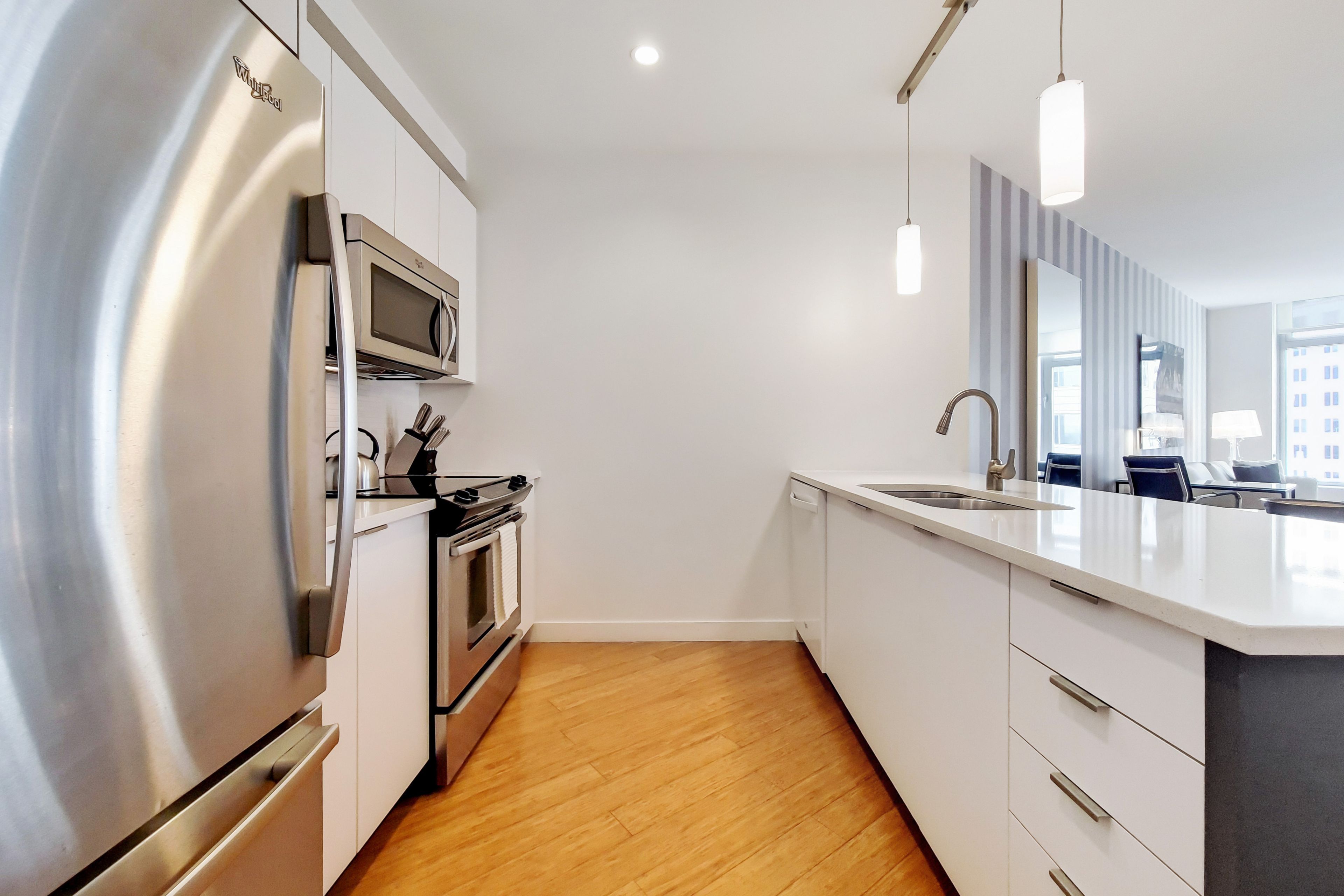 A modern kitchen with stainless steel appliances, a built-in oven, and a large island with a sink.