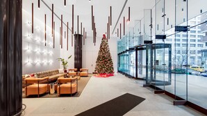 Un vestíbulo moderno con un árbol de Navidad, zona de estar y un ascensor de vidrio.