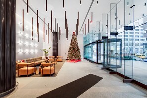 Una hall moderna con un albero di Natale, zona salotto e un ascensore in vetro.