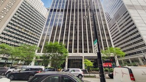 Un edificio alto y moderno con fachada de vidrio e indicación de una ruta ciclista.