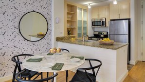 Una cocina compacta con una isla central, una mesa de comedor con sillas y un espejo grande.