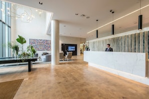 A modern reception area with a marble reception desk, seating area with sofas, and a colorful abstract wall art.