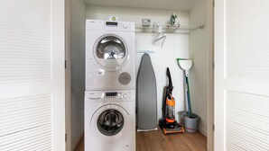 A laundry area with stacked washing machines and an ironing board. - Boston 2 Bedroom, Across from Fenway Park (Boston)