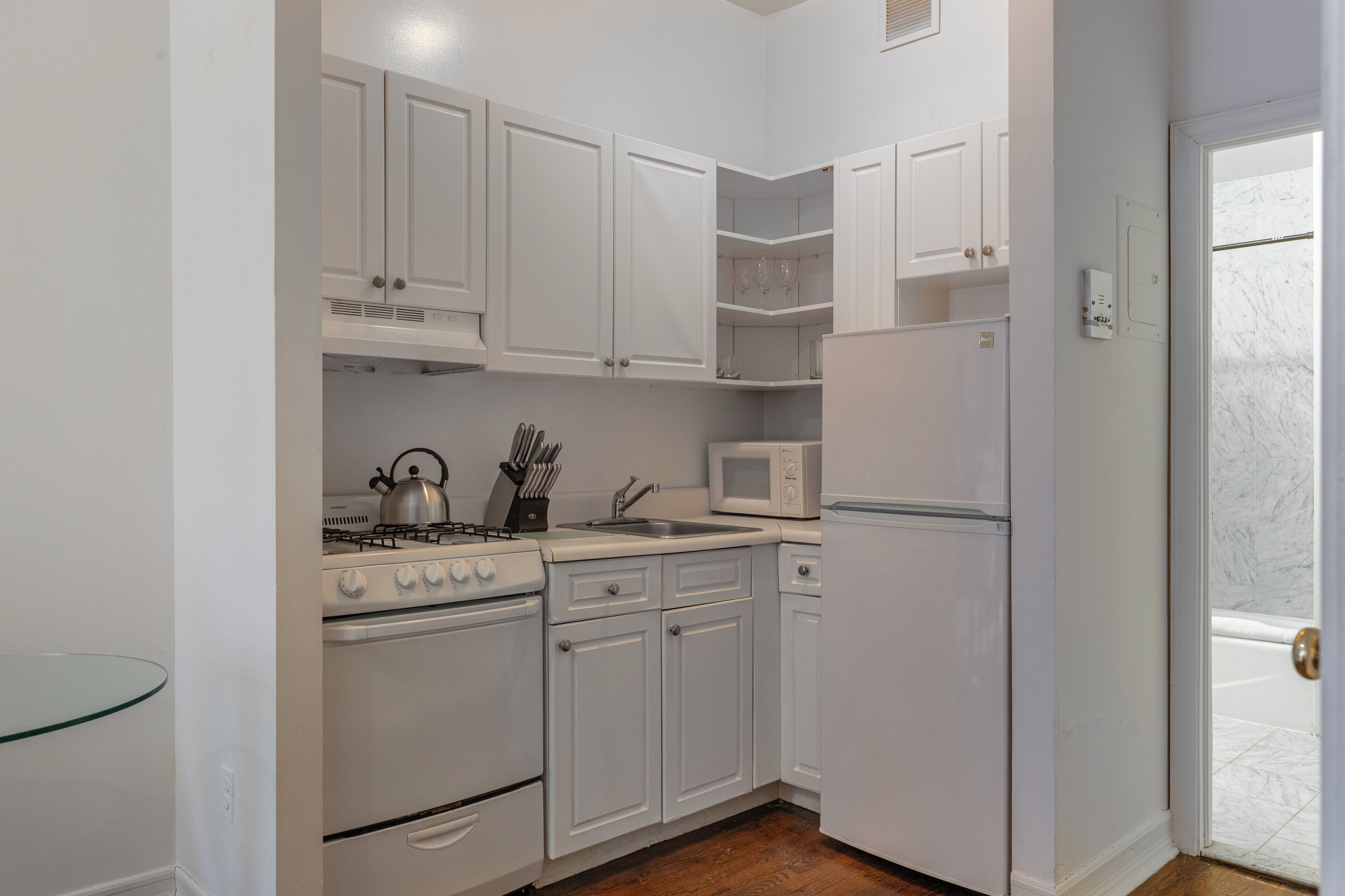 A compact kitchen with white cabinets, a stove, a microwave, and a refrigerator.