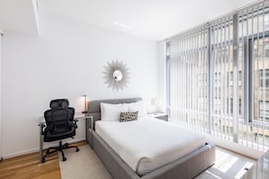 Een moderne slaapkamer met een bed, een bureau en een stoel.