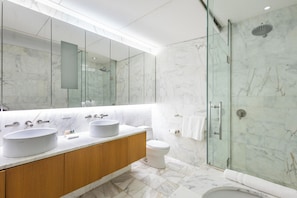 Een moderne badkamer met twee wastafels, een toilet en een douchecabine met glazen wanden.