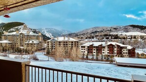 A snow-covered mountain town with multiple multi-story buildings, including a prominent hotel with a large central tower.