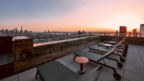 Una terraza en la azotea con mesas y sillas, con vistas al horizonte urbano.