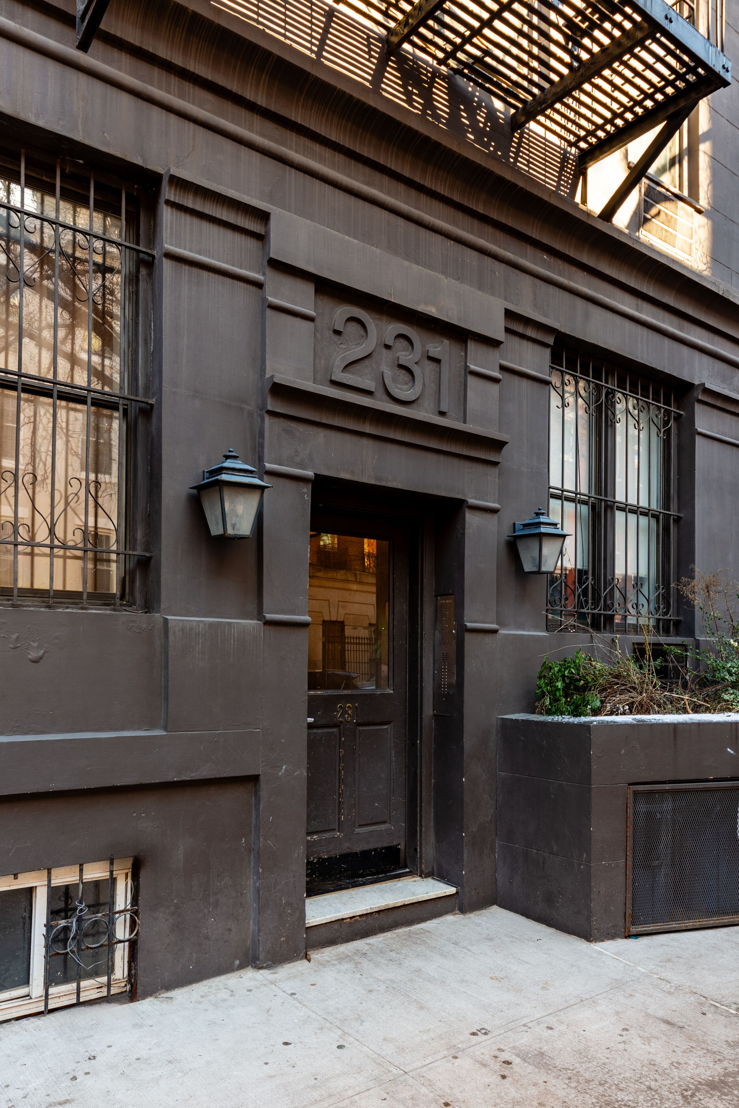 A building facade with a dark-colored entrance, a visible door number '281', and a small window with a metal grille.
