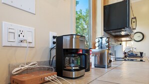 Una cuina amb una cafetera, un torradora i una caixa de fusta damunt el taulell.