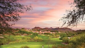 Un parcours de golf offrant une vue sur une ville et des montagnes en arrière-plan.