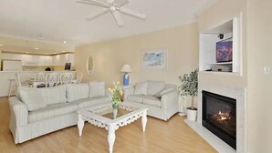 A living room with a fireplace, a ceiling fan, and a television mounted on the wall. - ⭐️Astoria 207 Ocean/Bayside Views Rooftop Pool Linens⭐️ (Ocean City)