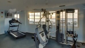 A gym with a treadmill, weight machines, and a view of the sea. - ⭐️Astoria 207 Ocean/Bayside Views Rooftop Pool Linens⭐️ (Ocean City)