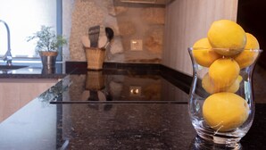 A kitchen with a glass vase containing lemons on a granite countertop. - Buganvília Loft - Quinta do Tapadinho (Cabeceiras de Basto)