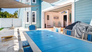 A backyard with a blue pool, a barbecue grill, and a covered patio area. - Steps to Beach & Pickleball • Pool, Game Room, Putting Green & Cart (Indian Rocks Beach)