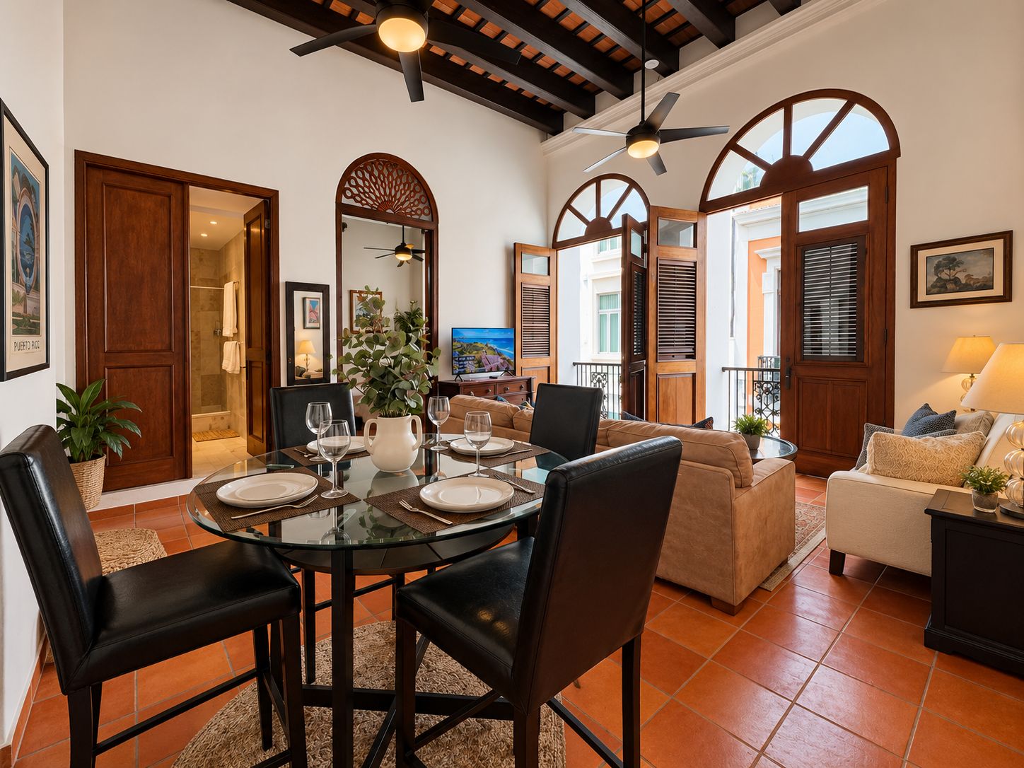 A spacious living area with a round glass table, leather chairs, a sofa, and a TV.