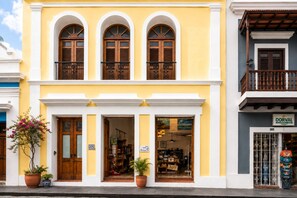 A yellow building with three arched windows and a balcony.