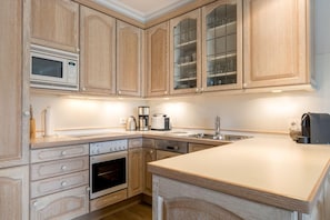 A kitchen with wooden cabinets, a microwave, a coffee maker, a toaster, and a dishwasher.