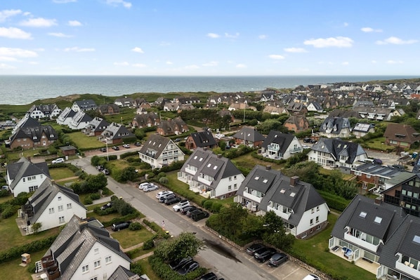 A residential area with houses, a road, and a body of water in the background.
