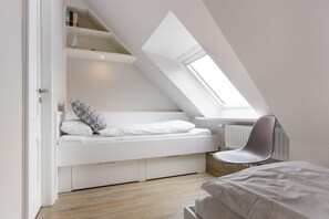 Ein modernes Schlafzimmer im Loft-Stil mit schrägem Dach, eingebauten Stauraumlösungen, einem Oberlicht und einer Heizkörper.