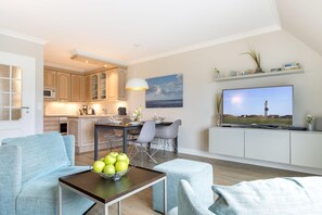 Ein modernes Wohnzimmer mit Essbereich, Küche und einem Fernseher, der einen Leuchtturm zeigt.