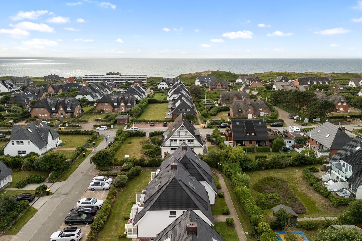 Ein Wohngebiet mit Häusern, einer Straße und Blick aufs Meer.