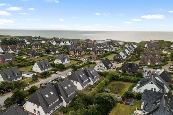 A coastal residential area with houses, a large building, and a view of the sea.