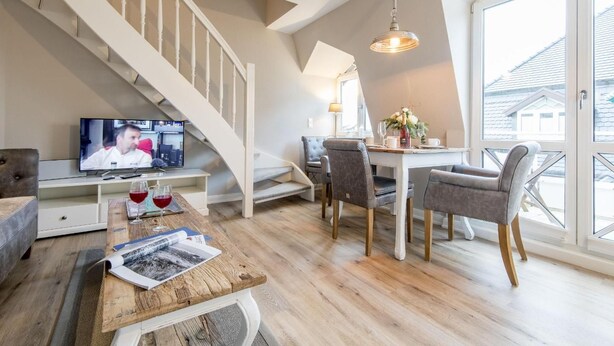 Un salon moderne avec un téléviseur, un coin repas et un escalier.