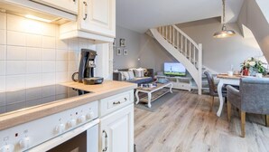 Une cuisine moderne avec des meubles blancs, une machine à café et un coin repas comprenant une table et des chaises en bois.