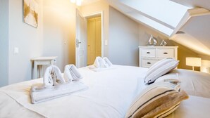 Une chambre d’hôtel avec un grand lit, une table de chevet, une commode et une lucarne.