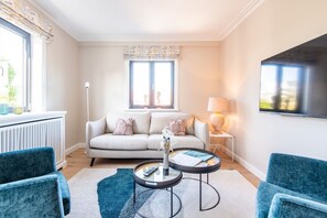 A modern living room with a sofa, two armchairs, a coffee table, a lamp, and a TV. - Stadthaus Boysenstraße, Whg. 5 - Stadthaus Boysen (Sylt)