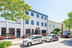 A building with a white facade and blue trim, featuring a restaurant named "Pinocchio" and a car rental service. - Stadthaus Boysenstraße, Whg. 5 - Stadthaus Boysen (Sylt)