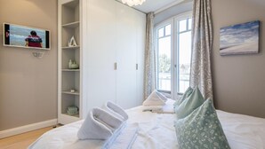 Een slaapkamer met een bed, een televisie, een kledingkast en een raam met gordijnen.