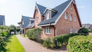 Een rij moderne bakstenen huizen met steile daken en een verzorgd tuinpad.
