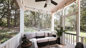 Une véranda abritée avec un canapé, une table et un ventilateur de plafond.