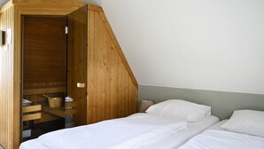 A bedroom with a wooden wardrobe, two beds, and a small table with a lamp. - Bungalowpark It Wiid by Interhome (Eernewoude)