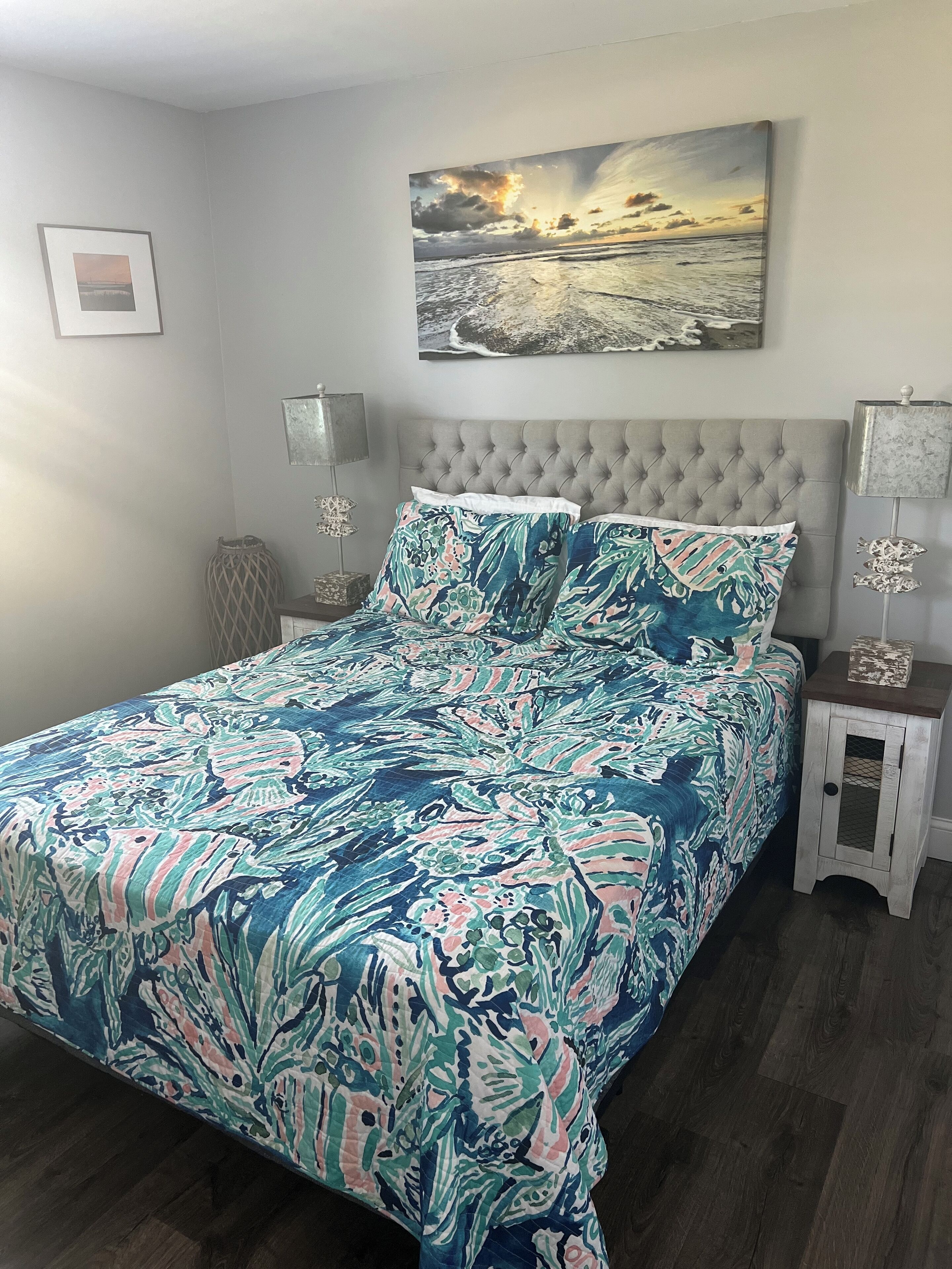 Une chambre à coucher avec un lit, une table de chevet, une lampe et un tableau au mur.