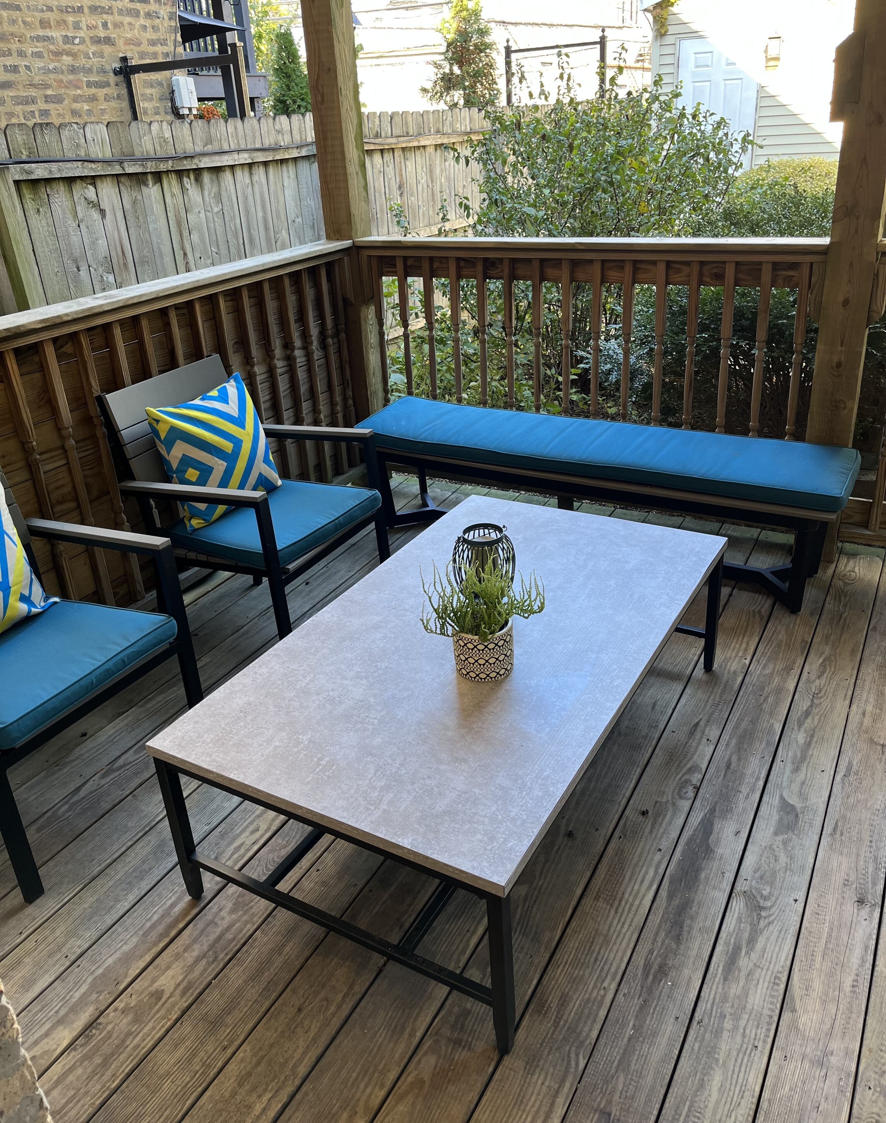 Una terraza de madera con una mesa, dos sillas y un banco.