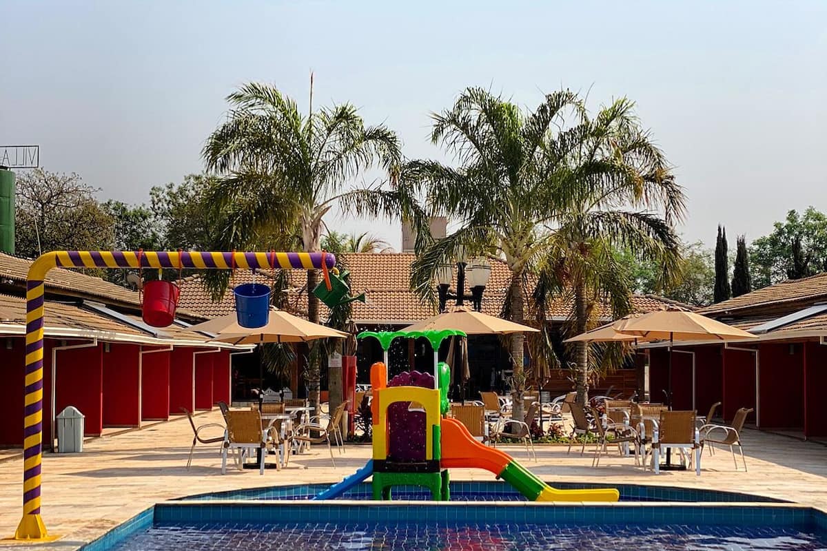 Zona de piscina con tobogán, sombrillas y mobiliario exterior.