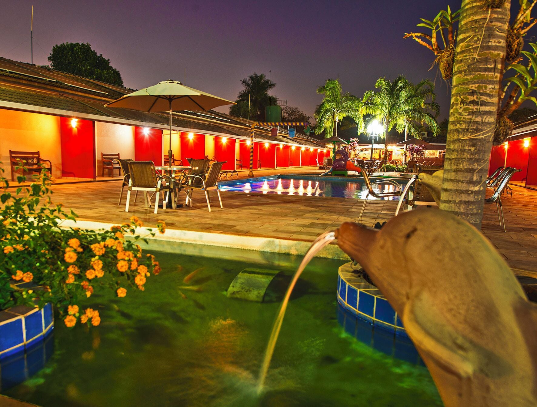 An outdoor pool area with lounge chairs and a small fountain.