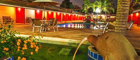 An outdoor pool area with lounge chairs and a small fountain.